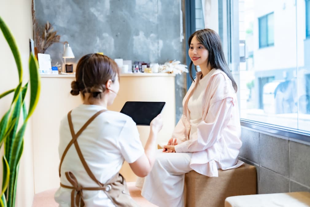 美容院で次回の予約の相談をするスタッフと客